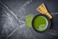 Top view on organic green matcha tea in black ceramic cup with bamboo whisk