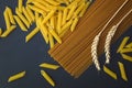 Top view Organic penne and whole wheat spaghetti pasta decorate by wheats on black slate stone plate Royalty Free Stock Photo