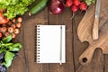 Top view of organic vegetables, chopping board and blank notepad with pencil Royalty Free Stock Photo