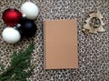 A top view original mockup with a blank notebook, a cypress branch and Christmas decorations on the white and brown background, a