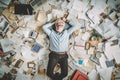 A top view of an overworked senior Scandinavian businessman lying on the floor that is full of papers and documents in