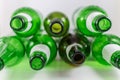 Top view of a pack of empty beer and wine green and brown glass bottles, with ripped labels on a white background. Reuse