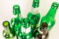 Top view of a pack of empty green and brown wine and beer glass bottles, with ripped labels on a white background. Reuse