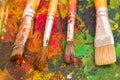 Top view of paint brushes over a color palette in a blurred background