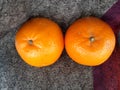 Top view of pair of fresh orange fruit placed on a blanket in daylight.