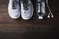 Top view of pair sports shoes, headphones and water bottle on black wood table background, Gray sneakers and accessories equipment