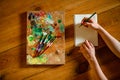 Top view of palette for oil and sketchbook on wooden table