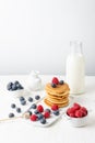 Top view of pancakes in stack with blueberries, raspberries and bottle of milk on table and white background, Royalty Free Stock Photo