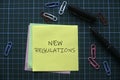 Top view of a paper clips,pen and memo notes written with New Regulations on green square background Royalty Free Stock Photo