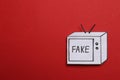 Top view of paper TV with word Fake on red background, space for text. Information warfare concept Royalty Free Stock Photo