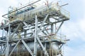 Two metal containers stand against the background of a gas processing plant