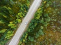 Top view at passenger car driving along dirt road between swamps in autumn forest Royalty Free Stock Photo