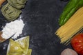 Top view of pasta background with spaghetti , ravioli,green pepper,onion and potato on floury dark background.Healthy homemade