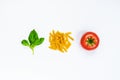 Top view of pasta ingredients over white background - raw fusilli, fresh basil and ripe tomatoe. Italian food concept. Royalty Free Stock Photo