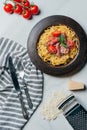 top view of pasta with mint leaves, jamon and cherry tomatoes covered by parmesan on plate at marble table with kitchen towel, Royalty Free Stock Photo