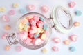 Top View of Pastel Color Heart and Flower Shaped Marshmallow Candies in a Glass Jar with Some Scattered on the Pale Blue Table Royalty Free Stock Photo