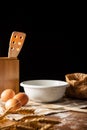 Top view of pastry objects, white bowl, eggs, flour and ears of wheat on cloth and wooden table, selective focus Royalty Free Stock Photo