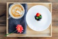 Top view Pavlova dessert mini cake, cup of latte coffee and fresh gerbera flower on the wooden tray with gray napkin on Royalty Free Stock Photo