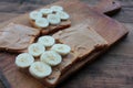 Top view of Peanut butter banana toasts on wooden background. Slices of whole wheat bran bread with peanut paste on cutting board Royalty Free Stock Photo