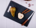 top view of pear slice with cinnamon sticks and kitchen knife on a black chopping board on white wooden background Royalty Free Stock Photo