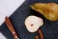 top view of pear slice with cinnamon sticks and kitchen knife on a black chopping board on white wooden background Royalty Free Stock Photo