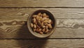 TOP VIEW: Peeled almonds fill wooden cup on a wooden table