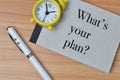Top view of clock, pen and notebook written with WHAT`S YOUR PLAN Royalty Free Stock Photo