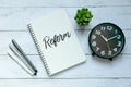 Top view of pen,clock,plant and notebook written with word Reform on white wooden background.