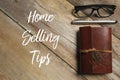 Top view of pen,glasses and notebook on wooden background written with Home Selling Tips.