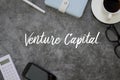 Top view of pen, notebook, a cup of coffee, glasses, mobile phone and calculator on grey grunge floor written with Venture Capital Royalty Free Stock Photo