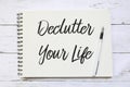 Top view of pen and notebook written with Declutter Your Life on wooden background.