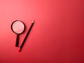 Top view pencil and magnifying glass on a red background Royalty Free Stock Photo