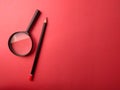 Top view pencil and magnifying glass on a red background Royalty Free Stock Photo