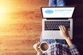 Top view of people working on notebook laptop computer from home on wooden floor with startup business and rocket logo on screen Royalty Free Stock Photo