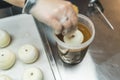 Top view of a person covering round doughnuts in caramel chocolate icing. Professional bakery.