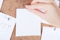 Top view of person hand attaching reminder sticky note to cork board. Cortical plank with sheets of paper. Empty place Royalty Free Stock Photo