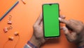 Top view of person hand suing smart phone on orange background