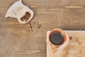 Top view of a person holding a cup of coffee with roasted coffee beans in a small sack on the table Royalty Free Stock Photo