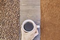 Top view of a person holding a cup of coffee with roasted and ground coffee beans on the table Royalty Free Stock Photo