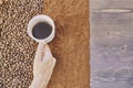 Top view of a person holding a cup of coffee with roasted and ground coffee beans on the table Royalty Free Stock Photo