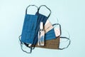 Top view of personal protection such as a pile of homemade textile masks and alcohol hand sanitizer on blue background. Health