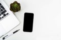 A phone with a screen mockup, a coffee cup of writing supplies, a pens, a notepad on a white wooden table background. Top view of Royalty Free Stock Photo