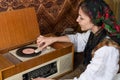 Top view photo of attractive female in national white dress who puts vinyl in old retro record player Royalty Free Stock Photo