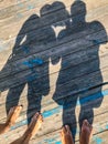 Top view, photo of bare feet and a pair of shadows on a wooden old floor. Photos on vacation, beach, summer