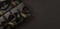 Top view photo of black gift boxes with black satin ribbon bow and golden confetti on isolated black background with text on