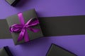 Top view photo of black giftbox with purple ribbon bow boxes on isolated violet and black background with copyspace Royalty Free Stock Photo