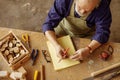 Top view photo of carpenter in old age holding little cross section of wooden