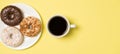 Top view photo of cup of coffee and plate with three different donuts on isolated light yellow background with empty space Royalty Free Stock Photo