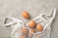 Top view photo of easter decorations white string bag with brown eggs on  grey concrete background with copyspace Royalty Free Stock Photo