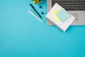 Top view photo of flowerpot binder clips pens reminder and sticker notes paper on laptop on isolated pastel blue background with